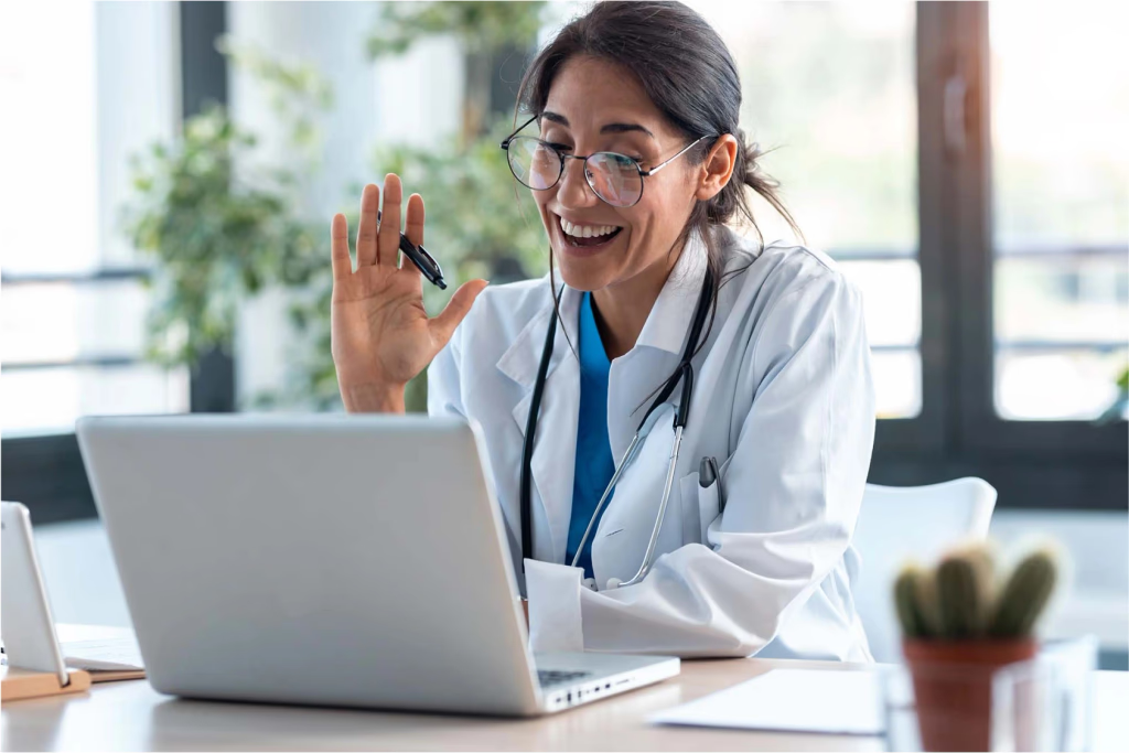 Médica sorrindo em videochamada pelo laptop
