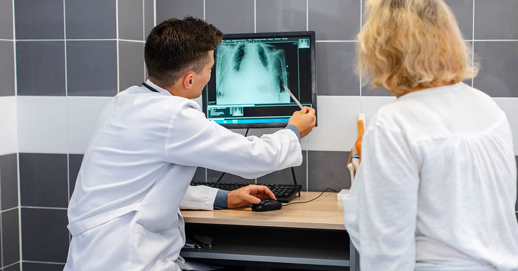 Médico mostrando um raio-x em tela para paciente